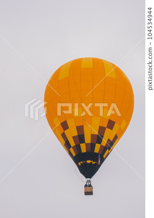 Colorful hot air balloon flying against grey sky at Winter aerostat festival Colorful hot air balloon flying against grey sky at Winter aerostat festival 104534944