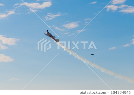Light aircraft flying in blue sky and doing stunts 104534945