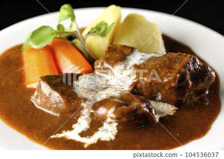 Watercress, carrot, potato garnish and fresh cream-covered thick-sliced beef tongue beef stew photographed against a black background Watercress, carrot, potato garnish and fresh cream-covered thick-sliced beef tongue beef stew photographed against a black background 104536037