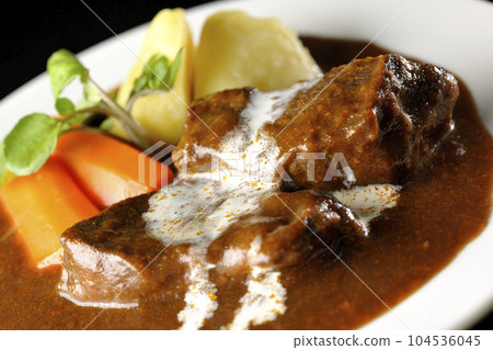 Watercress, carrot, potato garnish and fresh cream-covered thick-sliced beef tongue beef stew photographed against a black background 104536045