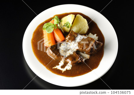 Watercress, carrot, potato garnish and fresh cream-covered thick-sliced beef tongue beef stew taken against a black background 104536075