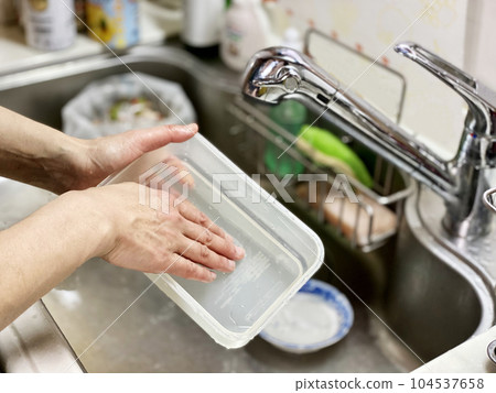 A hand confirming that a plastic storage container has been washed 104537658