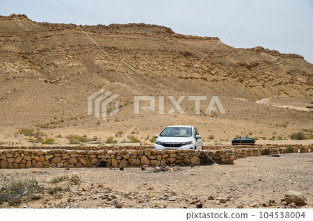 A white car stands on the side of a road in the Negev desert. A white car stands on the side of a road in the Negev desert. 104538004