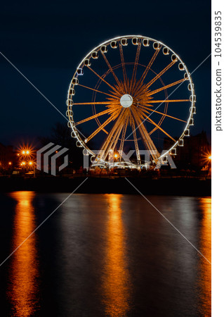 Gdansk Poland Ferris wheel in the old town of Gdansk at night evening dusk Reflection in river water Europe. Long exposure photo. City scenic view Illuminated attraction park and street Gdansk Poland Ferris wheel in the old town of Gdansk at night evening dusk Reflection in river water Europe. Long exposure photo. City scenic view Illuminated attraction park and street 104539835
