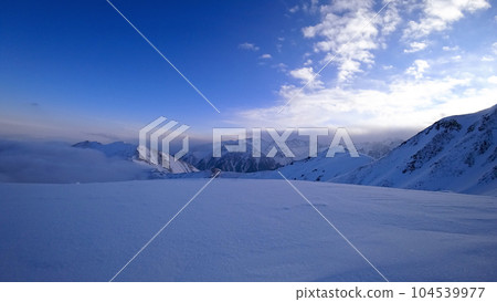 Ocean of clouds in snowy mountains at dawn Ocean of clouds in snowy mountains at dawn 104539977