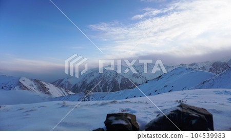 Ocean of clouds in snowy mountains at dawn Ocean of clouds in snowy mountains at dawn 104539983