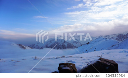 Ocean of clouds in snowy mountains at dawn 104539984
