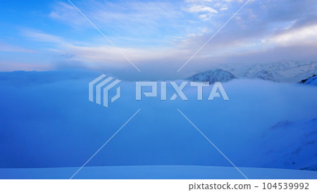Ocean of clouds in snowy mountains at dawn 104539992
