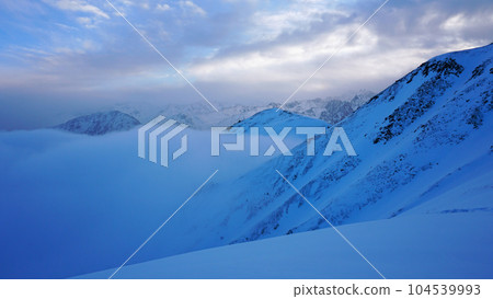 Ocean of clouds in snowy mountains at dawn Ocean of clouds in snowy mountains at dawn 104539993