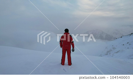 A climber in a red suit stands on top of mountain A climber in a red suit stands on top of mountain 104540003