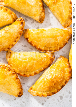 Freshly baked breakfast empanadas with eggs and sweet potato on the kitchen counter. Freshly baked breakfast empanadas with eggs and sweet potato on the kitchen counter. 104540217