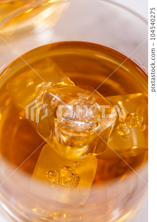 Scotch on the rocks in whiskey glass on a white marble surface. 104540275