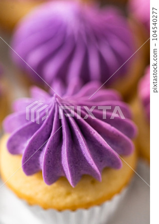 Freshly baked mini vanilla cupcakes with ombre pink buttercream frosting on a white cake stand. Freshly baked mini vanilla cupcakes with ombre pink buttercream frosting on a white cake stand. 104540277