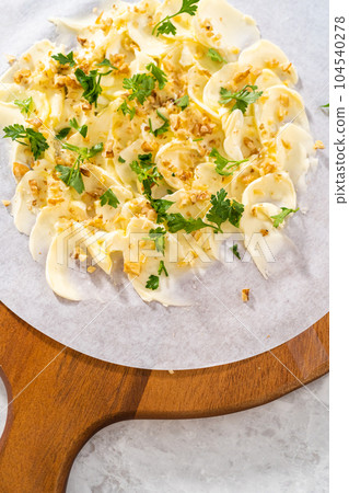Assembling butter board with vegetables and bread on a round wood cutting board. 104540278