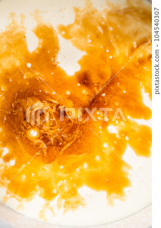 Heating whipped cream in a saucepan to make the white chocolate ganache frosting. 104540307