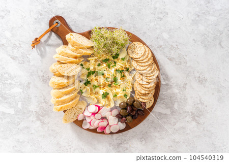 Flat lay. Butter board with vegetables and bread on a round wood cutting board. 104540319