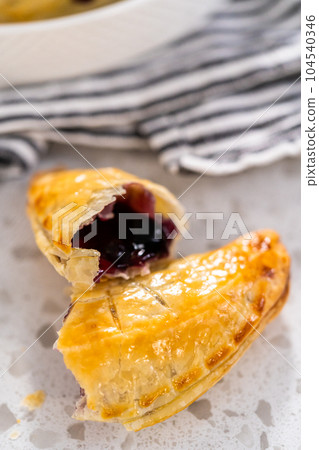 Freshly baked sweet empanadas with blueberries on the kitchen counter. 104540346