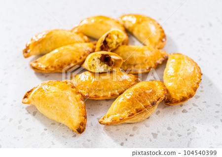 Freshly baked breakfast empanadas with eggs and sweet potato on the kitchen counter. 104540399