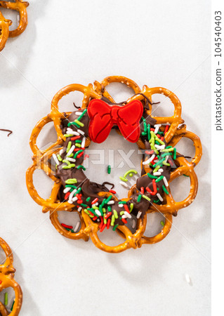Dipping pretzels twists into melted chocolate to make a chocolate pretzel Christmas wreath. 104540403