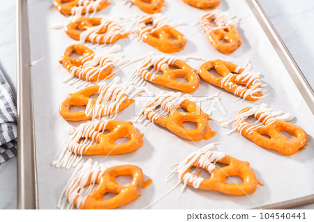 Drizzling melted chocolate over chocolate-dipped pretzels twists. 104540441