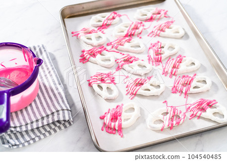 Drizzling melted chocolate over chocolate-dipped pretzels twists. 104540485