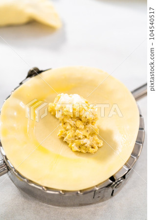 Filling empanada dough with egg filling to make breakfast empanadas with eggs and sweet potato. 104540517