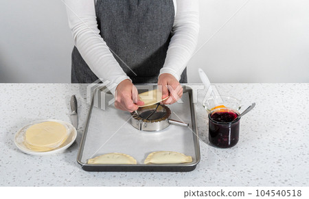 Filling empanada dough with blueberry pie filling to make sweet empanadas with blueberries. 104540518