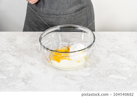 Mixing ingredients in a glass mixing bowl to bake s'mores cupcakes. 104540682