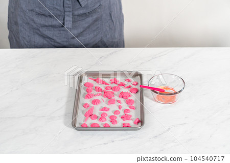 Painting sea-shaped chocolates with glittery luster to decorate chocolate-dipped pretzels twists. Painting sea-shaped chocolates with glittery luster to decorate chocolate-dipped pretzels twists. 104540717