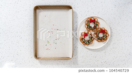 Flat lay. Removing a chocolate pretzel Christmas wreath from the parchment paper. 104540729