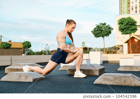 Fitness woman lunges forward outdoors 104542396