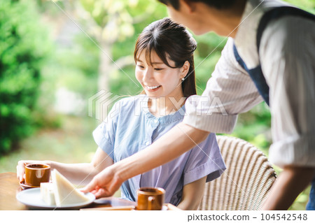 A young woman in a dress and a cafe clerk enjoying coffee at a cafe A young woman in a dress and a cafe clerk enjoying coffee at a cafe 104542548