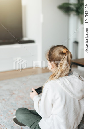 Girl playing video game at home Girl playing video game at home 104543409
