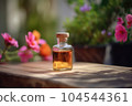 Fragrant Rose Geranium Essential Oil in small transparent glass Bottle on a wooden surface next to fresh Pink Geranium Flowers in full bloom, Garden background with Copy space. 104544361