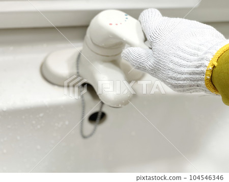 A hand with gloves holding a faucet A hand with gloves holding a faucet 104546346