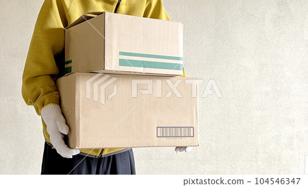 A person with work gloves holding two cardboard boxes_Wide A person with work gloves holding two cardboard boxes_Wide 104546347