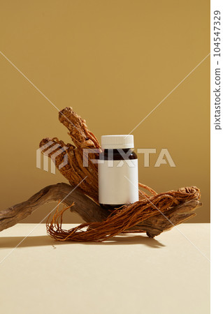 Minimalist style for product brand presentation with traditional medicine on brown background. Angelica sinensis root (Dang Gui) decorated with an amber bottle without label for design. Minimalist style for product brand presentation with traditional medicine on brown background. Angelica sinensis root (Dang Gui) decorated with an amber bottle without label for design. 104547329