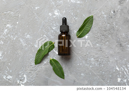 Natural Mint Essential Oil in a Glass Bottle. organic cosmetics with herbal extracts of mint on colored background 104548134