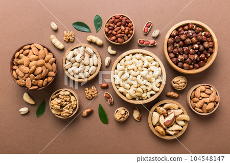 mixed nuts in wooden bowl. Mix of various nuts on colored background. pistachios, cashews, walnuts, hazelnuts, peanuts and brazil nuts 104548147