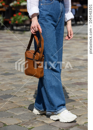 photo of a woman with a small brown leather bag. 104548301