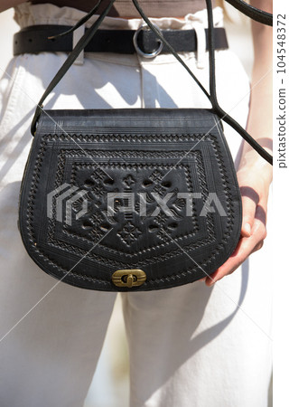 small black women's leather bag with a carved pattern. selective focus 104548372