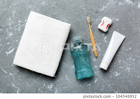 Mouthwash and other oral hygiene products on colored table top view with copy space. Flat lay. Dental hygiene. Oral care products and space for text on light background. concept Mouthwash and other oral hygiene products on colored table top view with copy space. Flat lay. Dental hygiene. Oral care products and space for text on light background. concept 104548952