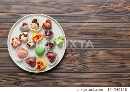 Plate with different chocolate on colored background. Assortment of fine chocolates top view vith copy space Health and obesity concept Plate with different chocolate on colored background. Assortment of fine chocolates top view vith copy space Health and obesity concept 104549138