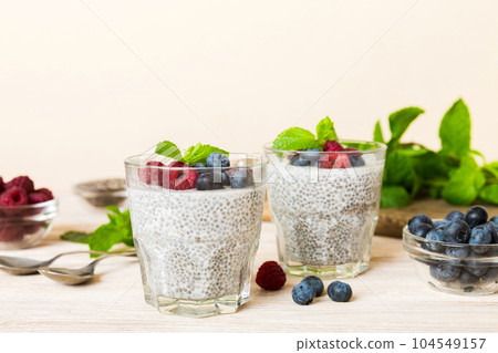 Healthy breakfast or morning with chia seeds vanilla pudding raspberry and blueberry berries on table background, vegetarian food, diet and health concept. Chia pudding with raspberry and blueberry Healthy breakfast or morning with chia seeds vanilla pudding raspberry and blueberry berries on table background, vegetarian food, diet and health concept. Chia pudding with raspberry and blueberry 104549157
