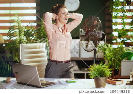 smiling modern female employee at work with electric fan 104549218