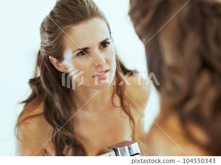 Concerned young woman looking in mirror 104550343
