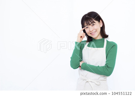 三十多歲的家庭主婦穿著圍裙,在白色背景前微笑著思考 三十多歲的家庭主婦穿著圍裙,在白色背景前微笑著思考 104551122