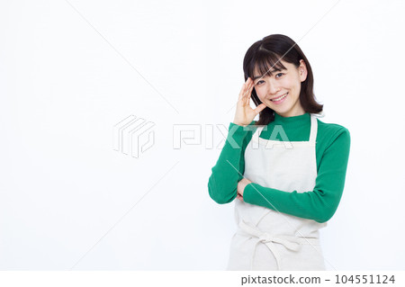 三十多歲的家庭主婦穿著圍裙，在白色背景前微笑著思考 104551124