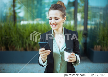 happy business woman near office building using smartphone happy business woman near office building using smartphone 104551463