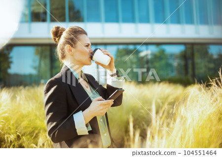 modern female worker near office building using smartphone 104551464